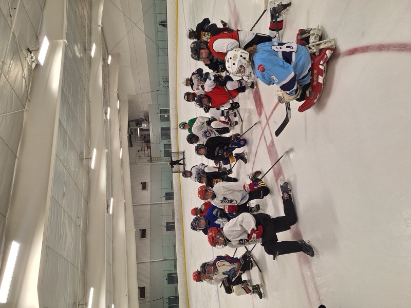 Players kneeling on the ice for instruction at an ABG summer camp